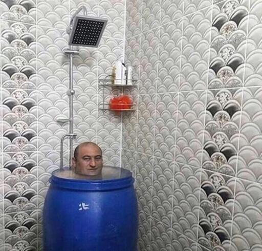 Man soaking in blue barrel in a shower