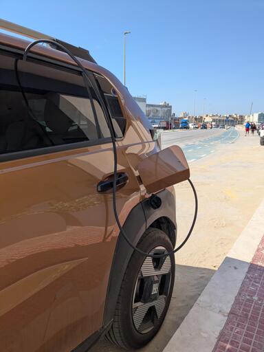 EV being charged through a cable that disappears inside the rear left door though the window suggesting it's charged from its own power source.