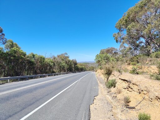 On the side of a road, looking down a long hill in the middle of nowhere